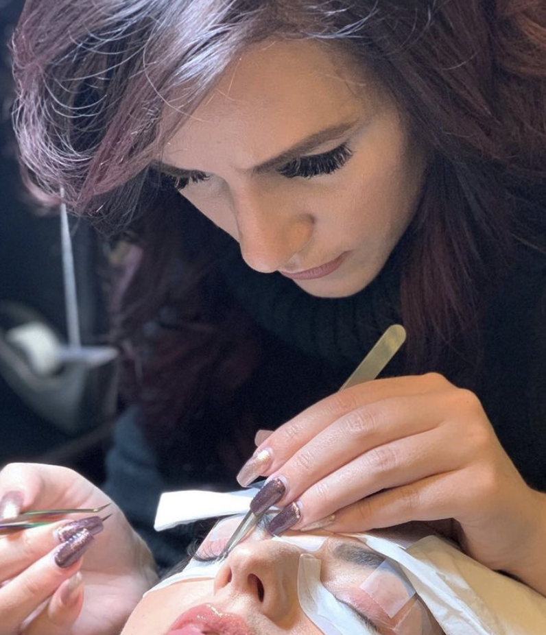 This is a photo of a lash technician adding individual lashes to the customers real lashes for extra volume  